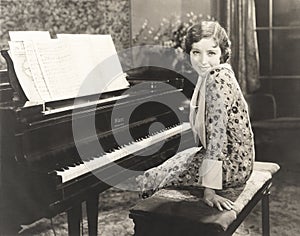 Smiling woman sitting by piano at home