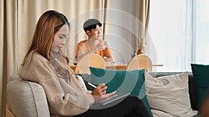 Smiling woman sitting on sofa and surfing in tenet with digital tablet.