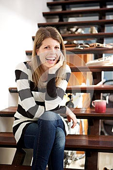 Smiling woman sitting on stairs at home