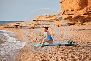 Smiling woman sitting on surfboard in bikini ready to catch wave. Hot summer holiday, beach relax and adventure concept