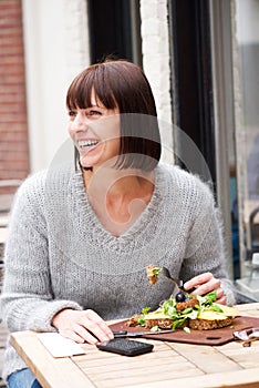 Smiling woman sitting at table eating food