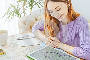 Smiling woman sitting at table looking at tablet with map of travel route.