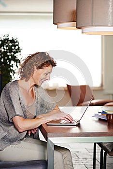 Smiling woman sitting at table working on laptop