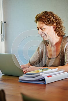 Smiling woman sitting at table working on laptop