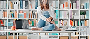 Smiling woman sitting on the top of the desk