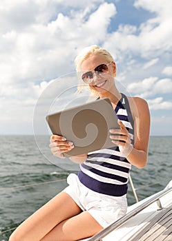 Smiling woman sitting on yacht with tablet pc