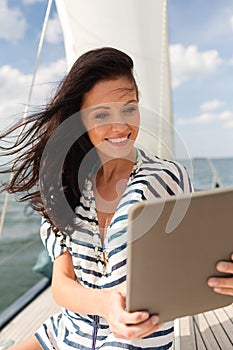 Smiling woman sitting on yacht with tablet pc