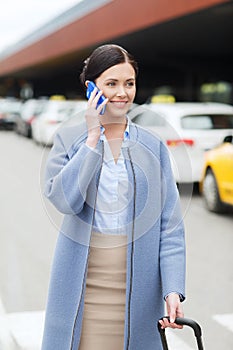 Smiling woman with smartphone over taxi in city