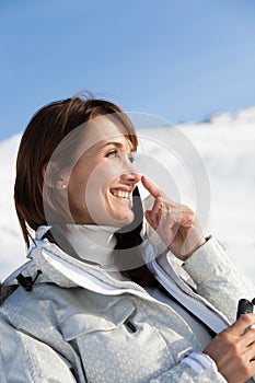 smiling Woman on the snow applying a protective cream