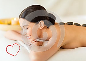 Smiling woman in spa salon with hot stones
