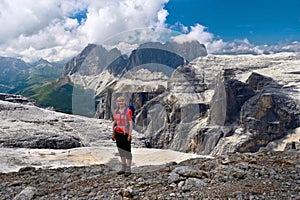 Smiling woman in sport clothes with a backpack feeling happy on her vacation in Italian Alps.