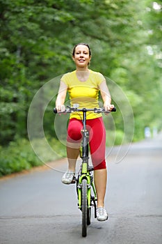 Smiling woman in sport clothes rides bicycle in