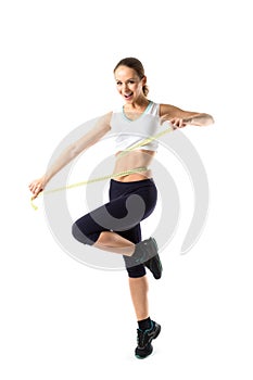 Smiling woman in sportswear measuring her waist measure tape.