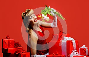 Smiling woman with spring flowers. Beautiful blonde girl in red dress with gift and bouquet of tulips. Spring flowers