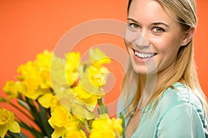 Smiling woman with spring yellow narcissus flowers