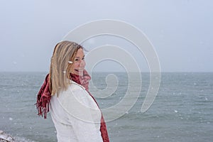smiling woman standing along lake michigan with fresh snow falling