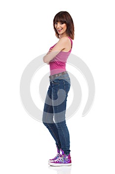 Smiling Woman Is Standing With Arms Crossed And Looking At Camera. Side View