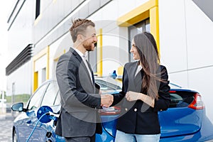 Smiling woman standing at the car and pointing at car seller tablet. She is picked right car for her she saw online.