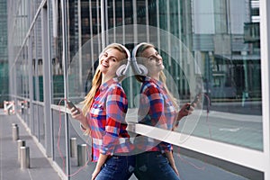 Smiling woman standing outside with phone and headphones