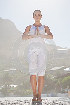 Smiling woman standing in tree pose on beach