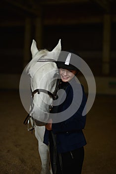 Smiling woman stands with white horse .