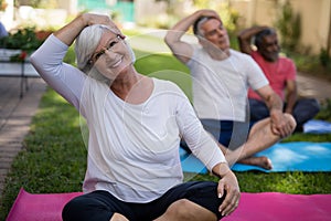 Smiling woman stretching head while exercising with friends