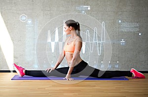 Smiling woman stretching leg on mat in gym