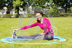 Smiling woman stretching leg on mat outdoors