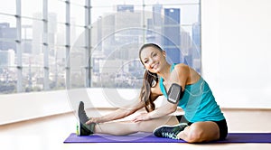 Smiling woman stretching leg on mat over gym