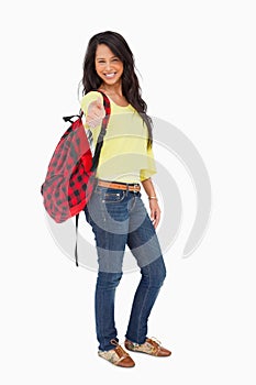 Smiling woman student thumb-up with a backpack