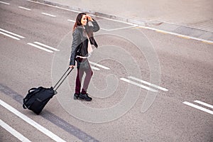 Smiling woman with suitcase crossing the street