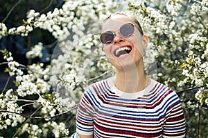 Smiling woman in sunglasses on background of blossoming apple tree