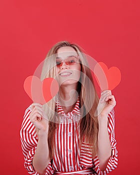 Smiling woman in sunglasses with red heart in hands.