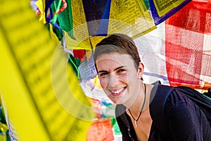 Smiling woman surrounded by tibetan prayer flags, Boudhanath, Kathmandu, Nepal