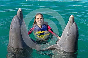 Smiling woman swimming with dolphins in blue water