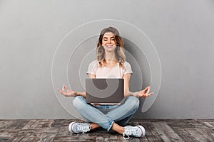 Smiling woman in t-shirt sitting on floor with laptop computer
