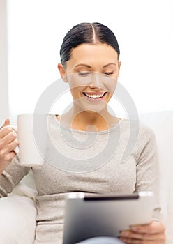 Smiling woman with tablet pc computer and cup