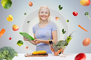 Smiling woman with tablet pc cooking vegetables