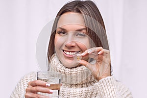 Smiling woman taking a pill with cod liver oil omega-3. Vitamin D, D3, fish oil
