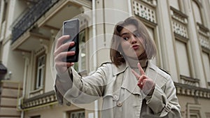 Smiling woman taking selfie on urban street. Girl pouting lips for phone camera.