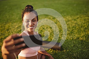 Smiling woman taking selfies in a park after doing yoga