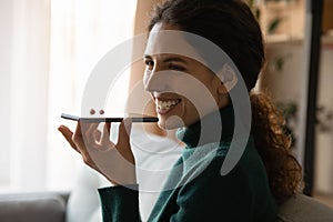 Smiling woman talk on loudspeaker on cellphone