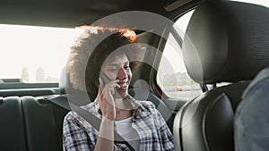 Smiling woman talking on the phone in the backseat of a car. Slow motion