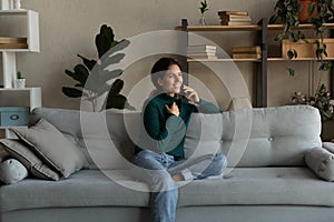Smiling woman talking on phone, enjoying conversation, sitting on couch
