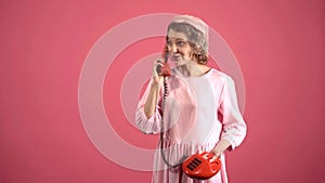 Smiling woman talking on retro telephone isolated on pink. Portrait of young pretty woman pinup girl talking on Retro