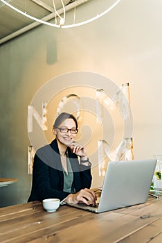 Smiling woman talking on smart phone. Businesswoman sitting at coffee shop and making a phone call