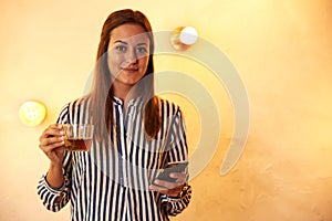 Smiling woman with tea and cellphone