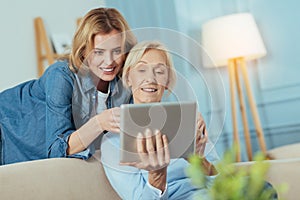 Smiling woman teaching her grandmother how to use a modern device