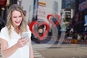 Smiling woman texting on mobile phone with digitally generated red hearts