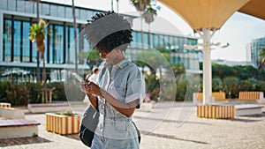 Smiling woman texting mobile phone on go sunny day closeup. Happy girl messaging